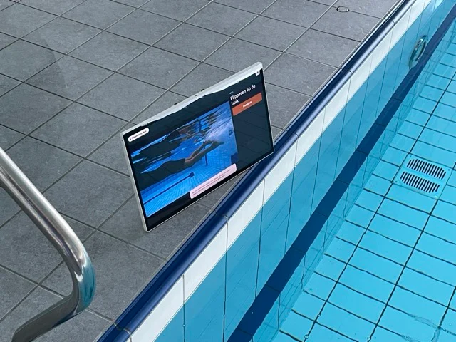 Tablet on the pool edge showing a swimming video demonstration in Studio